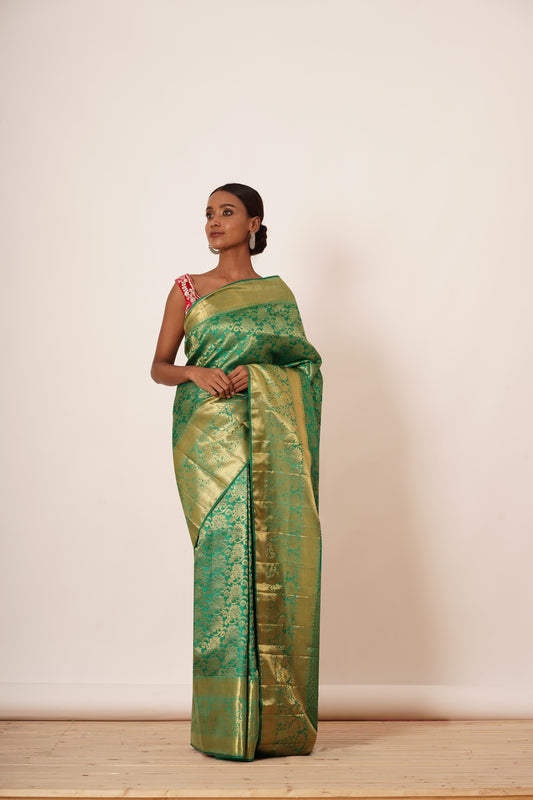 Peacock green dharmavaram silk saree with all over gold brocade with a velvet red off shoulder zari embroidery